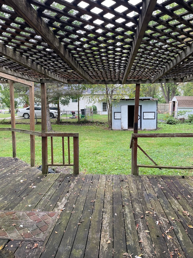 deck featuring a pergola, a storage unit, and a lawn