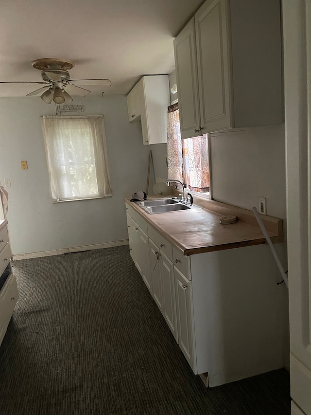 kitchen with dark colored carpet, ceiling fan, white cabinetry, and sink