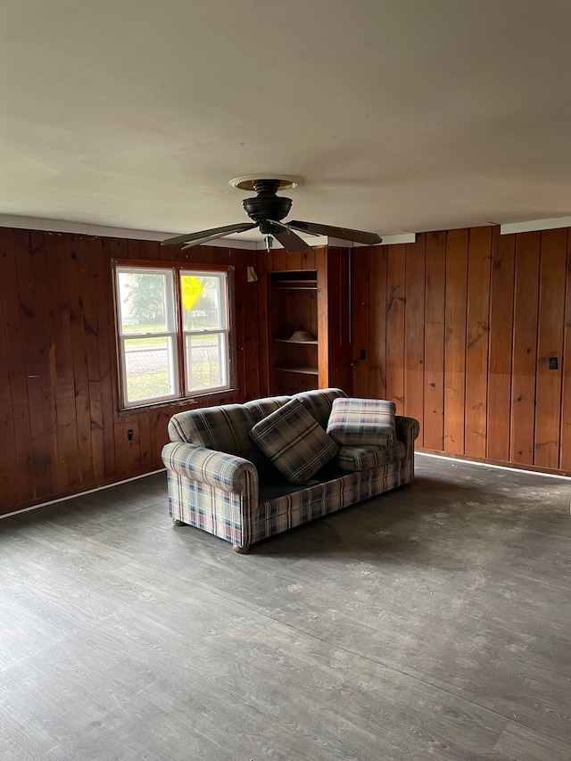 unfurnished living room featuring ceiling fan and wood walls