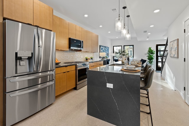 kitchen with a kitchen bar, stainless steel appliances, tasteful backsplash, hanging light fixtures, and a kitchen island with sink