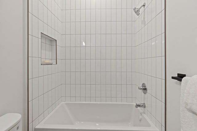 bathroom with toilet and tiled shower / bath