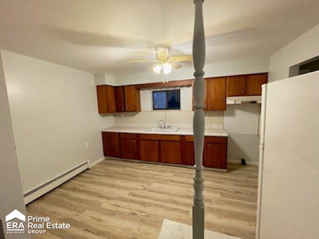 kitchen featuring ceiling fan, baseboard heating, sink, light hardwood / wood-style flooring, and white fridge