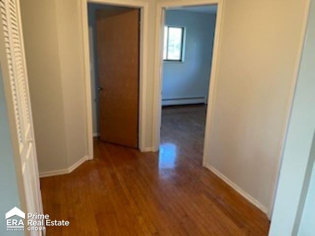 corridor featuring baseboard heating and hardwood / wood-style floors