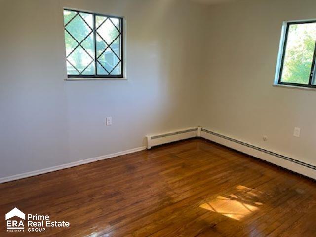 unfurnished room with a baseboard radiator and dark wood-type flooring