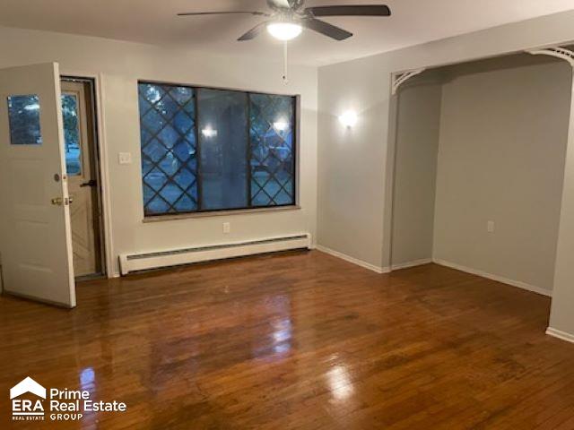 interior space featuring ceiling fan, dark wood-type flooring, and a baseboard radiator