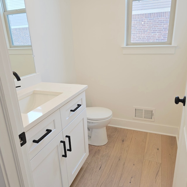 bathroom featuring toilet, plenty of natural light, hardwood / wood-style floors, and vanity