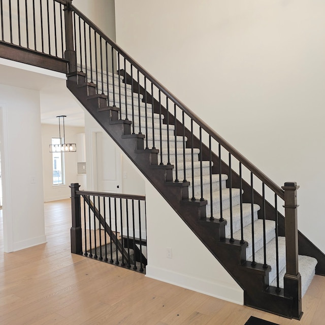 stairs with an inviting chandelier and wood-type flooring