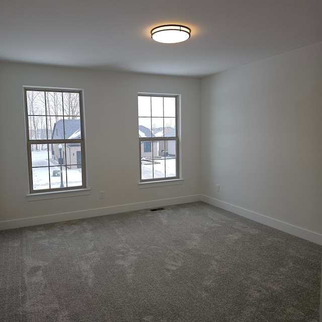 unfurnished room with dark colored carpet