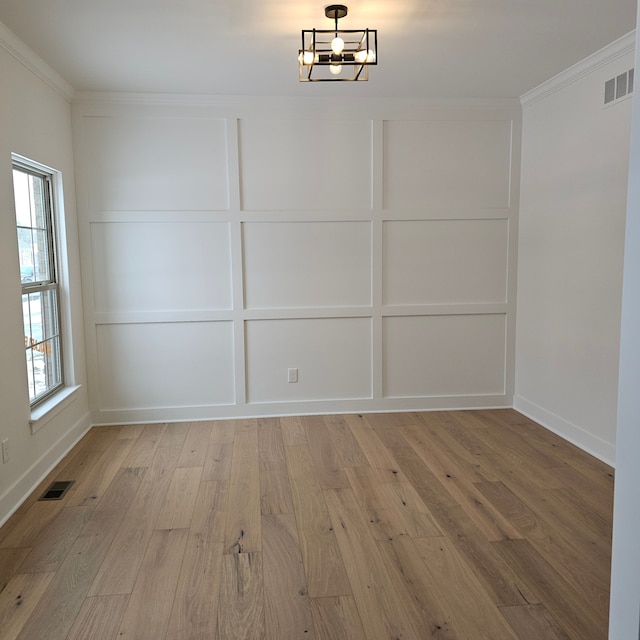 spare room featuring light hardwood / wood-style floors, ornamental molding, and an inviting chandelier