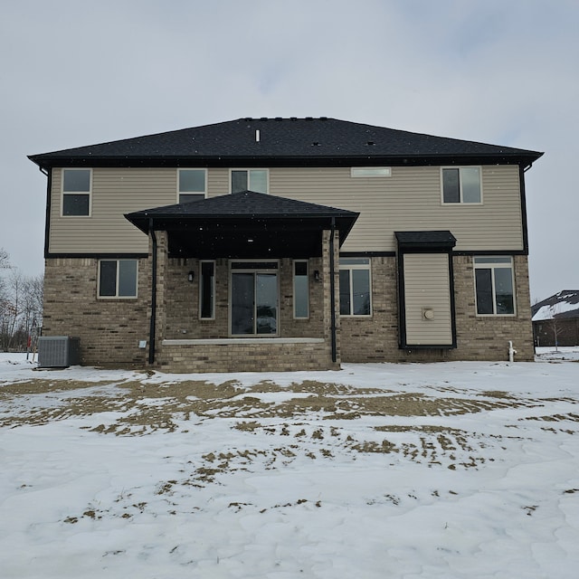 snow covered house featuring cooling unit