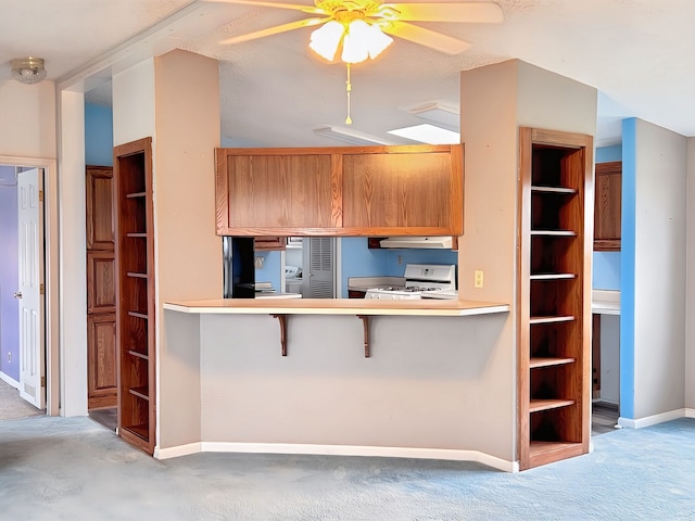 kitchen with ceiling fan, kitchen peninsula, light colored carpet, a breakfast bar, and range