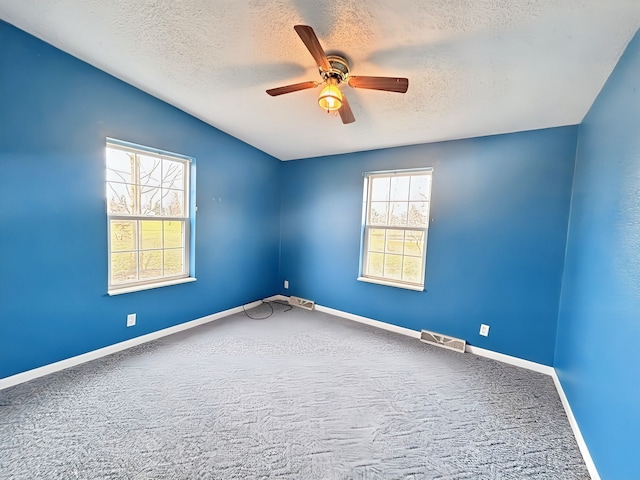 carpeted spare room with ceiling fan and a textured ceiling