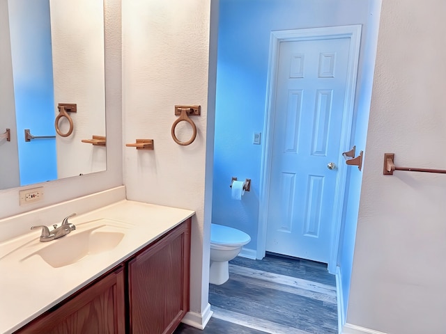 bathroom with vanity, toilet, and wood-type flooring