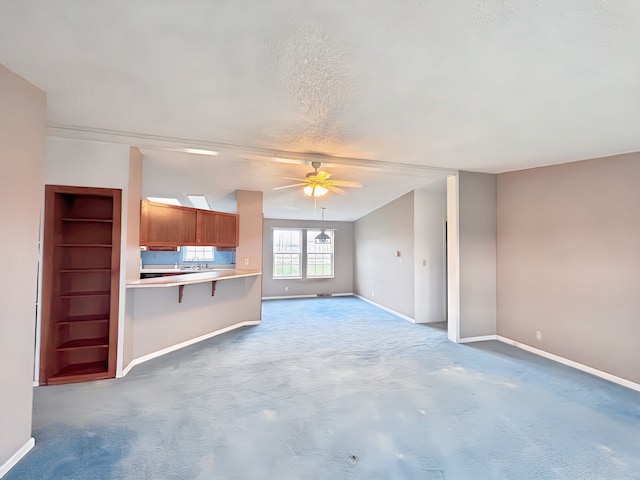 unfurnished living room featuring a textured ceiling, carpet floors, and ceiling fan