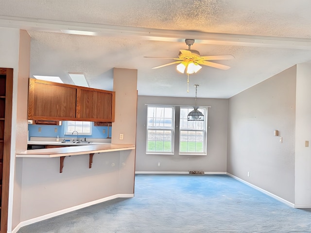 kitchen with carpet flooring, ceiling fan, a textured ceiling, and decorative light fixtures