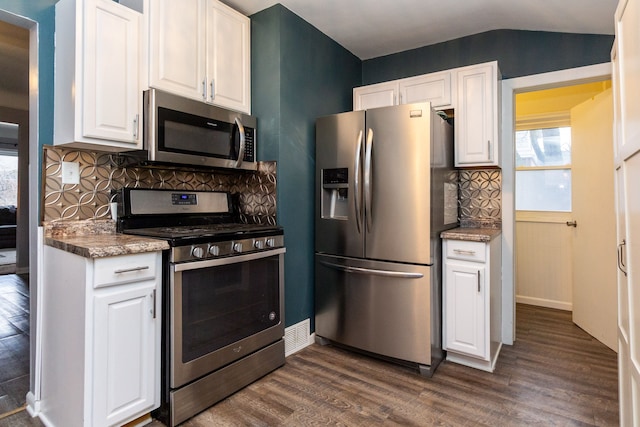 kitchen featuring white cabinets, lofted ceiling, backsplash, and appliances with stainless steel finishes