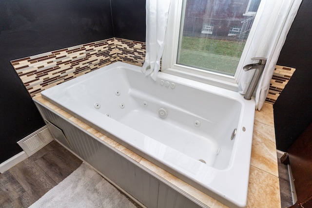 bathroom with a washtub and hardwood / wood-style flooring