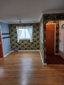 unfurnished dining area featuring wood-type flooring and ornamental molding