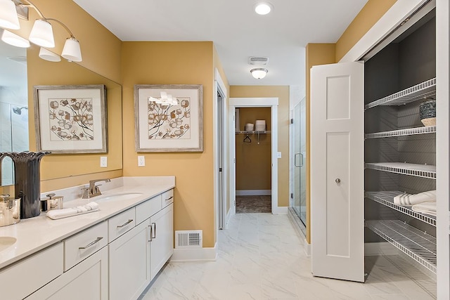 bathroom featuring a shower with door and vanity