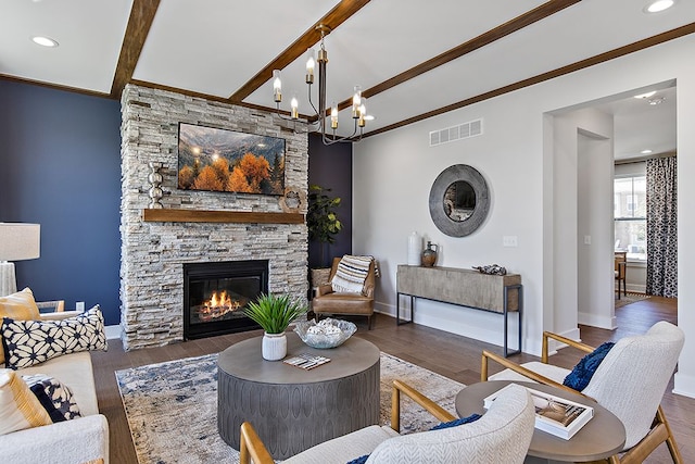 living room featuring dark wood-type flooring, a stone fireplace, crown molding, beamed ceiling, and a notable chandelier