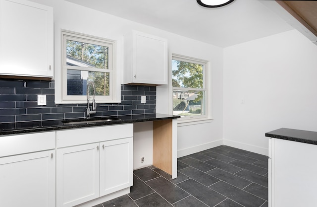 kitchen featuring a healthy amount of sunlight, white cabinetry, sink, and tasteful backsplash