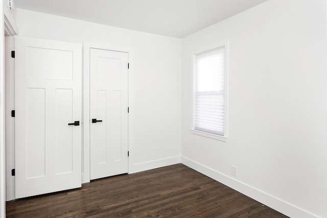 unfurnished bedroom with a closet and dark wood-type flooring