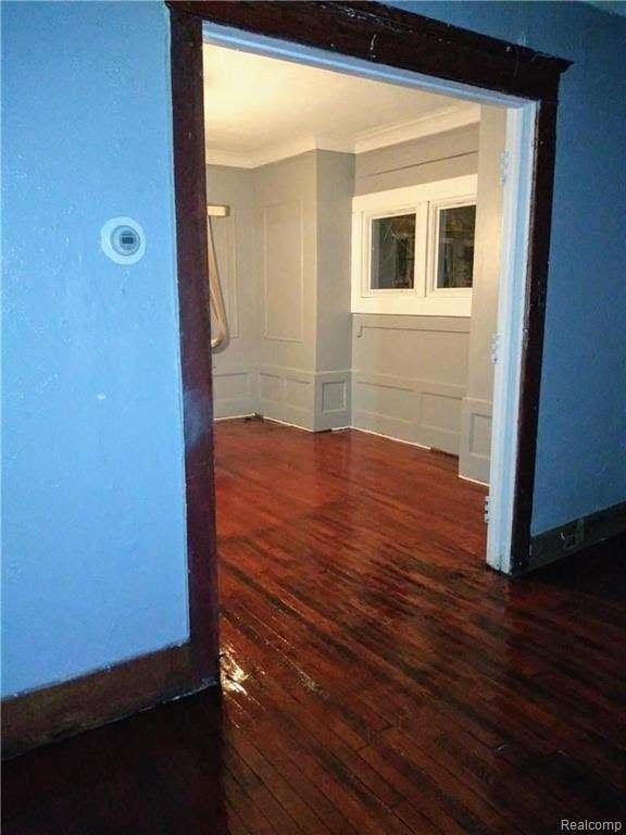 spare room featuring crown molding and dark wood-type flooring