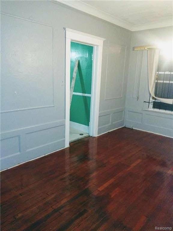 unfurnished room with ornamental molding and dark wood-type flooring