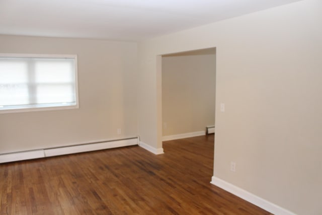 unfurnished room with dark hardwood / wood-style flooring and a baseboard heating unit