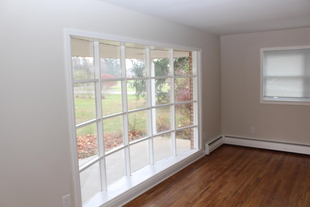 spare room featuring dark hardwood / wood-style flooring, a baseboard radiator, and plenty of natural light