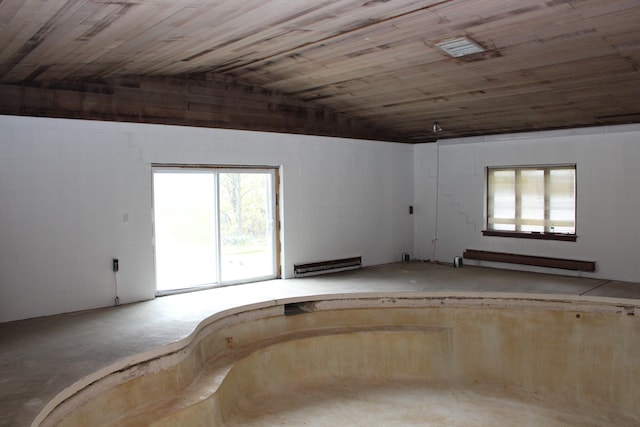 empty room featuring wooden ceiling, lofted ceiling, a baseboard radiator, and concrete floors