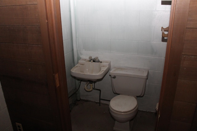 bathroom featuring toilet, tile walls, and sink