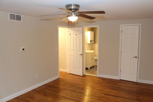 unfurnished bedroom with wood-type flooring, ensuite bathroom, and ceiling fan