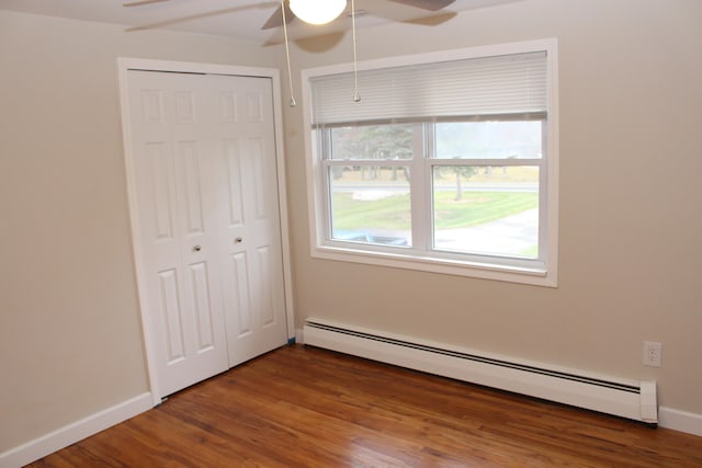 unfurnished bedroom featuring ceiling fan, a closet, a baseboard radiator, and wood-type flooring