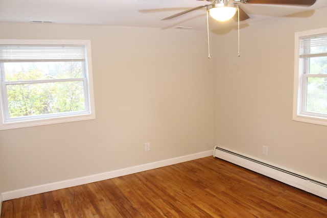 spare room with hardwood / wood-style flooring, ceiling fan, and a baseboard heating unit