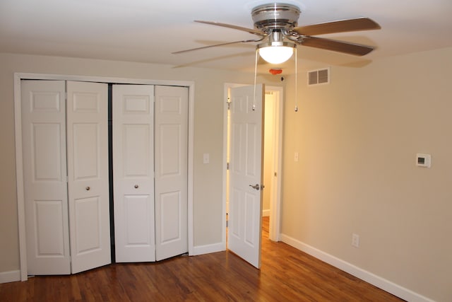 unfurnished bedroom with ceiling fan, dark wood-type flooring, and a closet