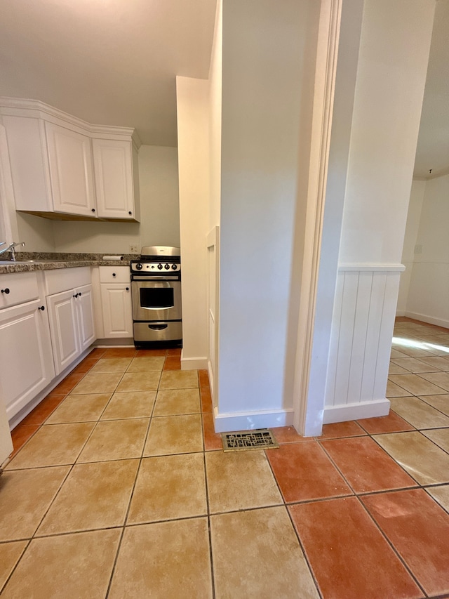 kitchen with white cabinetry, stainless steel stove, and light tile patterned flooring