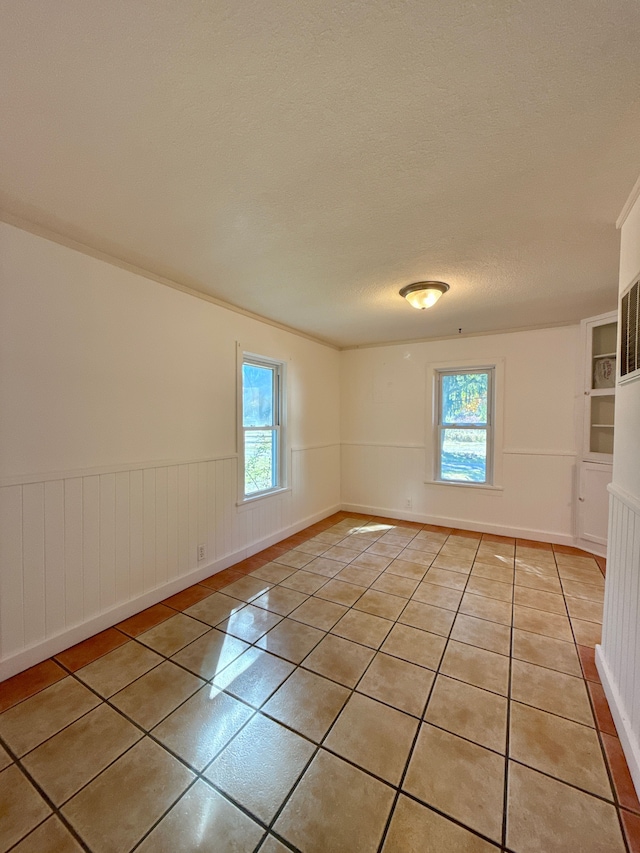 tiled spare room featuring a textured ceiling and plenty of natural light