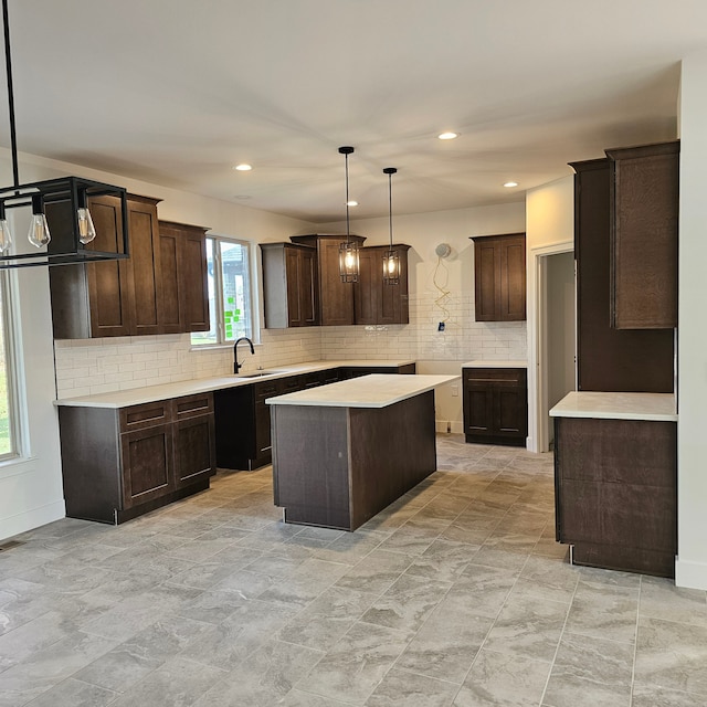 kitchen featuring pendant lighting, a kitchen island, sink, backsplash, and dark brown cabinets