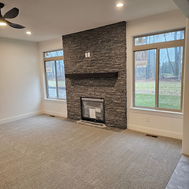 unfurnished living room featuring light colored carpet, a healthy amount of sunlight, and a fireplace