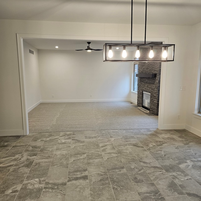 unfurnished living room with ceiling fan, carpet, and a fireplace