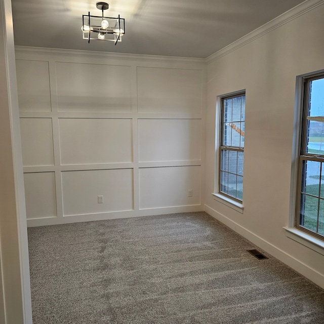 spare room with carpet floors, crown molding, and a notable chandelier