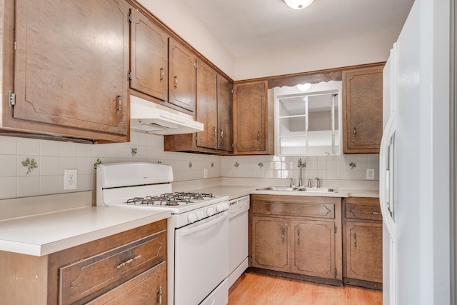 kitchen with tasteful backsplash, light hardwood / wood-style flooring, white appliances, and sink