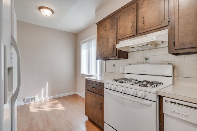 kitchen featuring white appliances, light hardwood / wood-style flooring, and backsplash