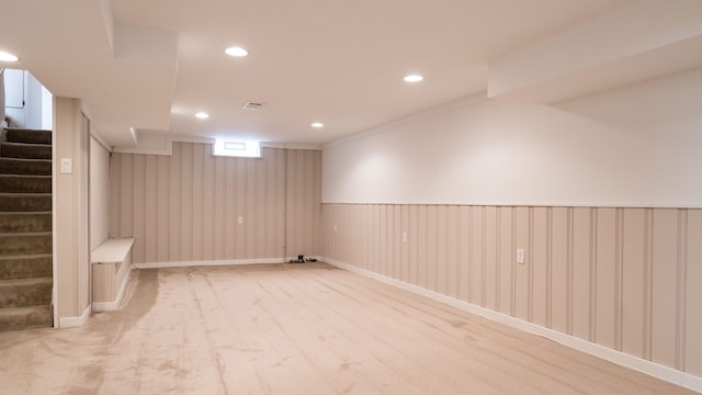 basement featuring wood walls and light carpet