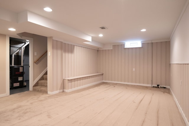 basement with carpet, crown molding, and wooden walls