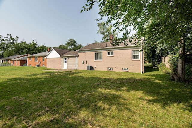 rear view of property with a lawn and cooling unit