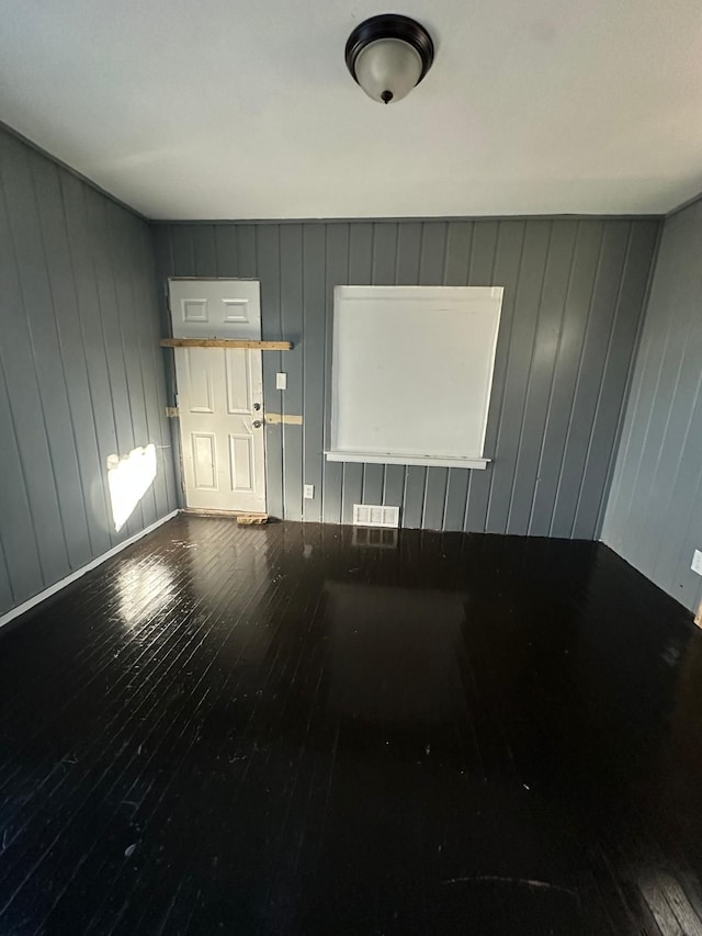 empty room with wooden walls and hardwood / wood-style flooring