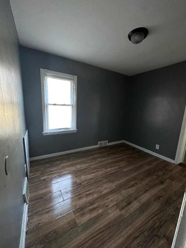 empty room with dark hardwood / wood-style flooring