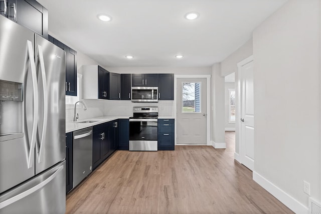 kitchen with light wood-type flooring, stainless steel appliances, tasteful backsplash, and sink